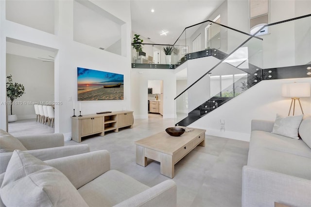 living room featuring recessed lighting, baseboards, stairs, and a towering ceiling