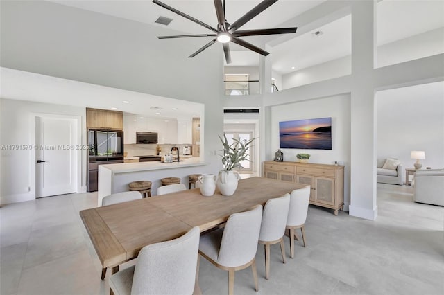 dining area featuring baseboards, a towering ceiling, ceiling fan, and visible vents