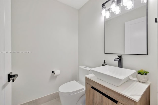 half bathroom with vanity, tile patterned flooring, baseboards, and toilet