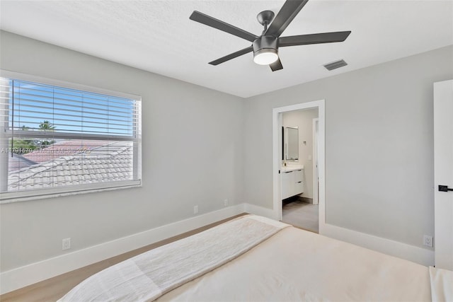 bedroom featuring baseboards, ensuite bathroom, ceiling fan, and visible vents