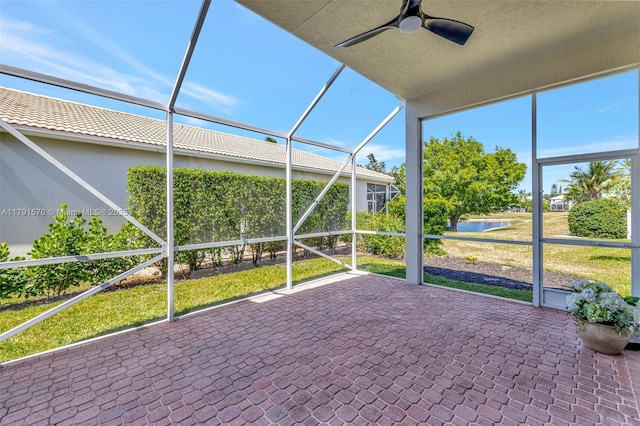 unfurnished sunroom featuring a ceiling fan and a water view