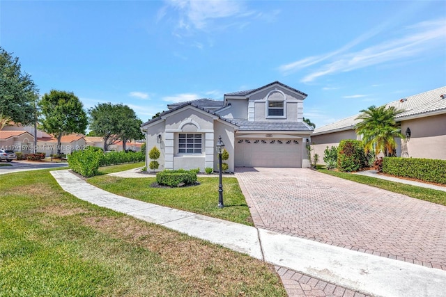 traditional home with a front lawn, a tile roof, a garage, stucco siding, and decorative driveway