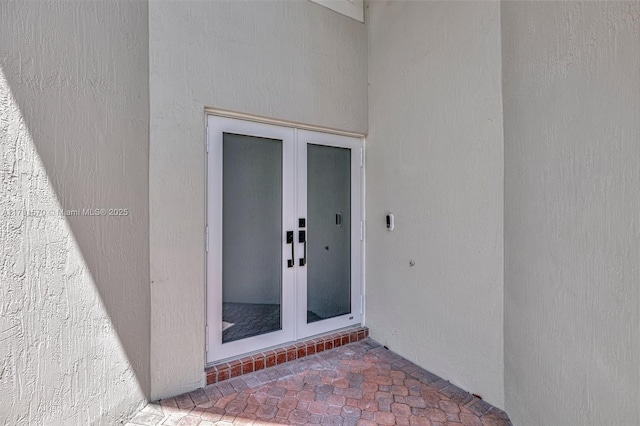 property entrance featuring stucco siding and french doors