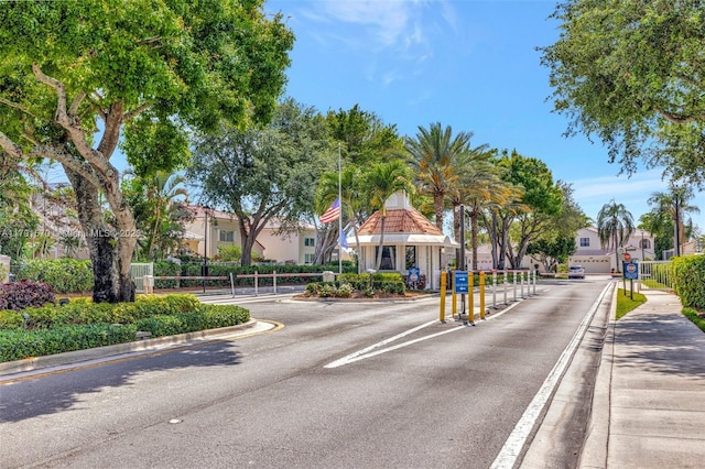 view of road with a gated entry, curbs, traffic signs, and a residential view