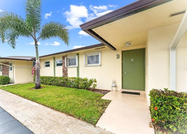 2935 W Crosley Dr Unit B, West Palm Beach, FL 33415 - view of exterior entry with stucco siding and a lawn