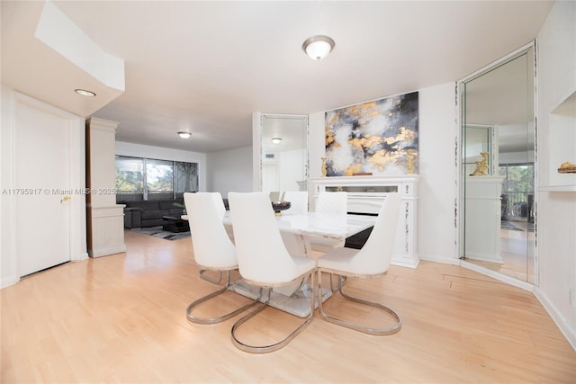 dining area with baseboards, wood finished floors, and a fireplace