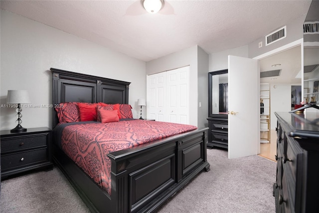 bedroom with visible vents, a textured ceiling, a closet, and light colored carpet