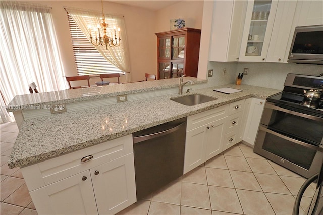 kitchen featuring stainless steel appliances, light tile patterned floors, white cabinetry, and a sink