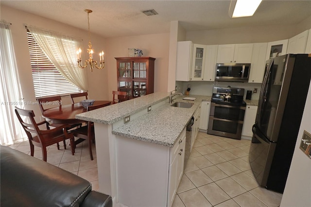 kitchen with visible vents, a sink, a peninsula, stainless steel appliances, and light tile patterned flooring