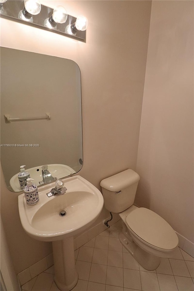 bathroom featuring baseboards, tile patterned flooring, and toilet