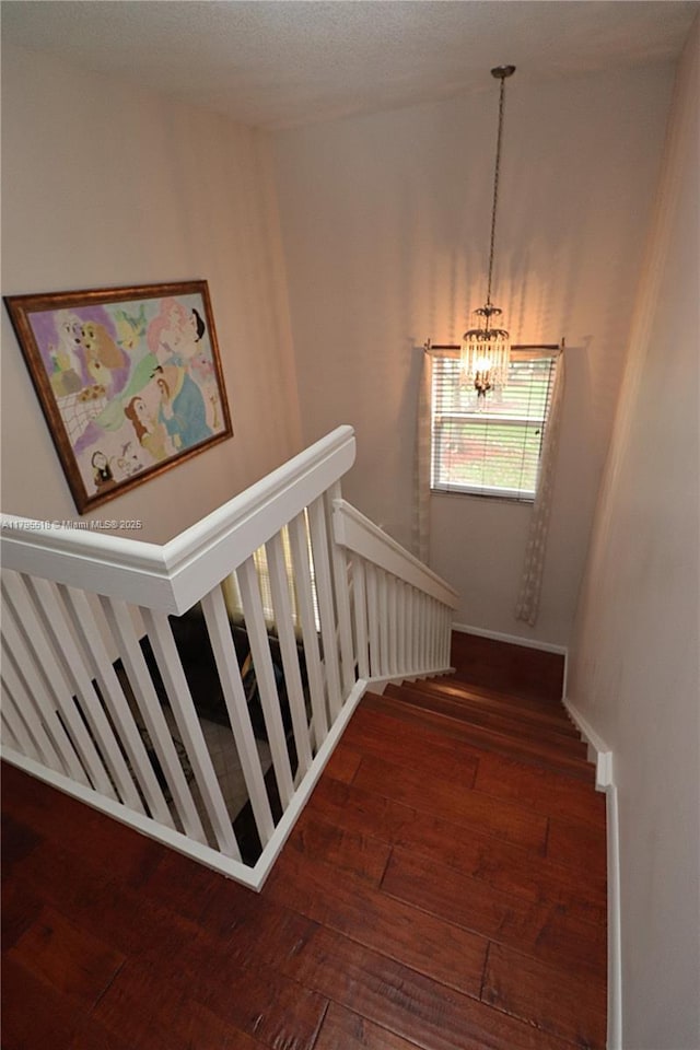 stairway with hardwood / wood-style flooring and a notable chandelier