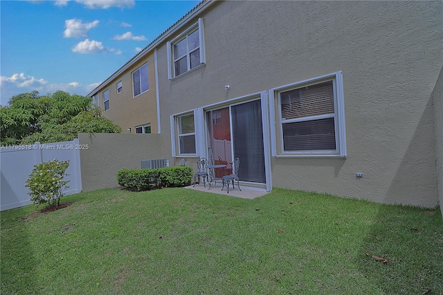 rear view of house featuring a lawn, a patio area, stucco siding, and fence