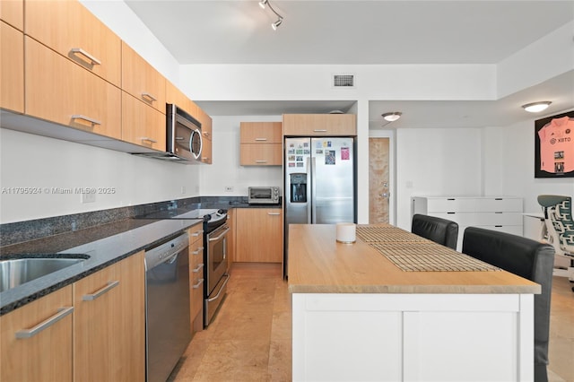 kitchen featuring appliances with stainless steel finishes, a center island, dark stone countertops, visible vents, and modern cabinets
