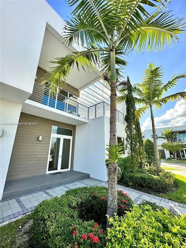 doorway to property featuring french doors, a balcony, and stucco siding