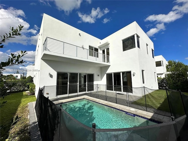 back of house with a fenced in pool, a balcony, a yard, a patio, and stucco siding