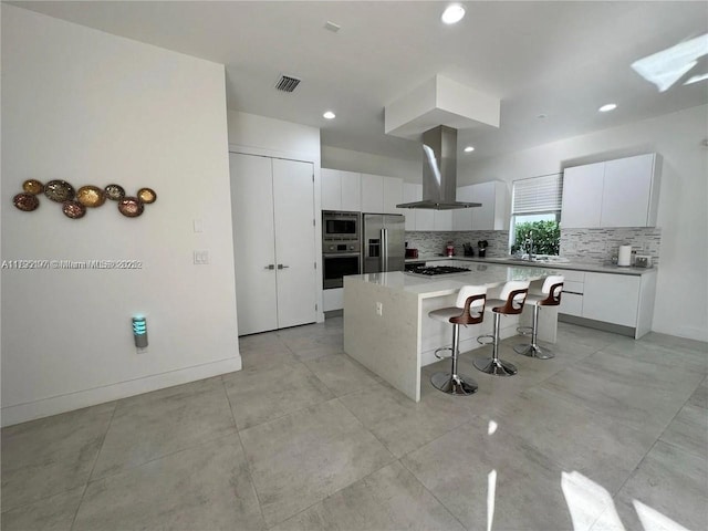 kitchen featuring a kitchen island, a breakfast bar area, white cabinets, tasteful backsplash, and appliances with stainless steel finishes