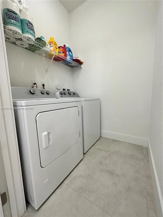 clothes washing area featuring laundry area, baseboards, and washing machine and clothes dryer