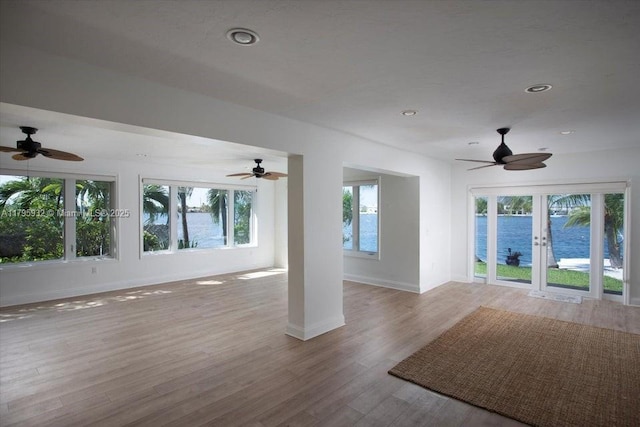 unfurnished living room with a ceiling fan, baseboards, and wood finished floors