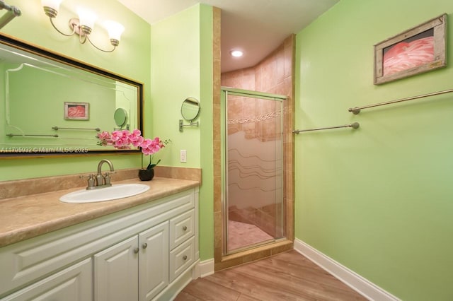 bathroom with baseboards, a shower stall, wood finished floors, and vanity