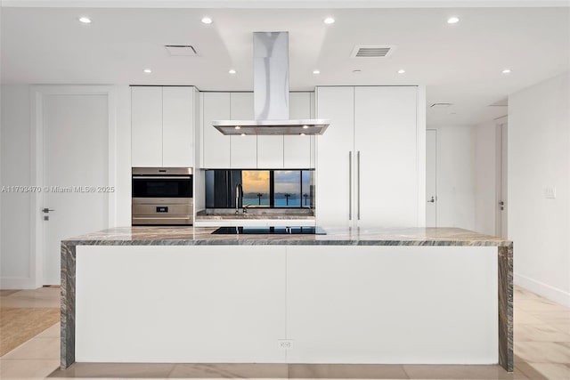 kitchen featuring white cabinets, stainless steel double oven, a large island, island exhaust hood, and modern cabinets