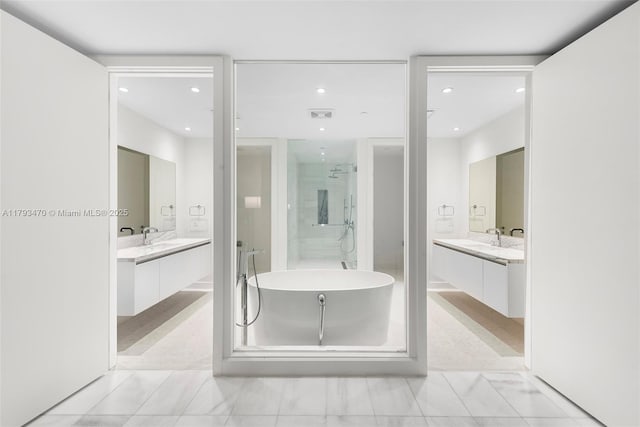 bathroom featuring recessed lighting, a soaking tub, two vanities, and a shower stall