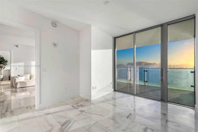 empty room with baseboards, floor to ceiling windows, and marble finish floor