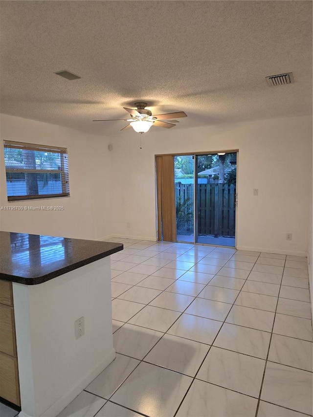 spare room featuring light tile patterned floors, ceiling fan, a textured ceiling, and visible vents