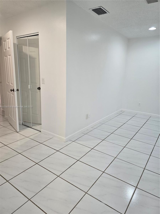 unfurnished room featuring visible vents, a textured ceiling, and baseboards