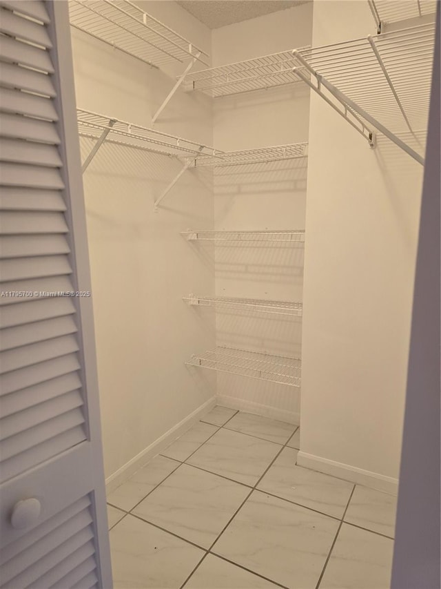 spacious closet featuring marble finish floor