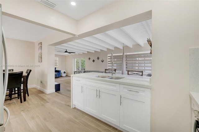 7295 W 14th Ct, Hialeah, FL 33014 - kitchen with a sink, beamed ceiling, light wood-style flooring, white cabinets, and open floor plan