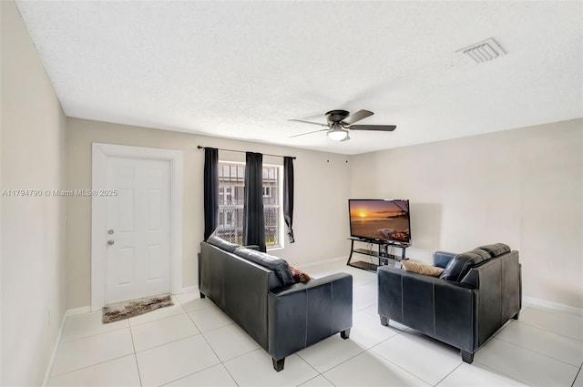 living room featuring visible vents, baseboards, ceiling fan, a textured ceiling, and light tile patterned floors