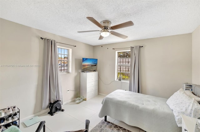 bedroom featuring a ceiling fan, baseboards, and a textured ceiling