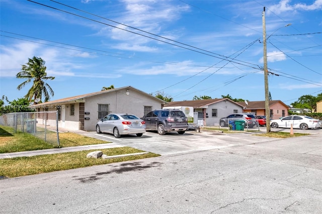 ranch-style house with stucco siding, fence, a residential view, and concrete driveway