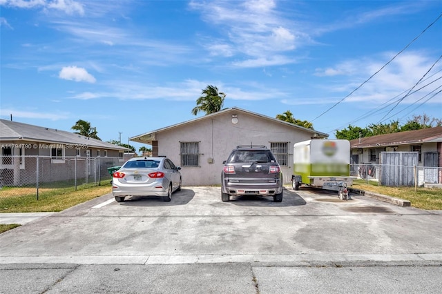 view of front facade with fence, stucco siding, and uncovered parking