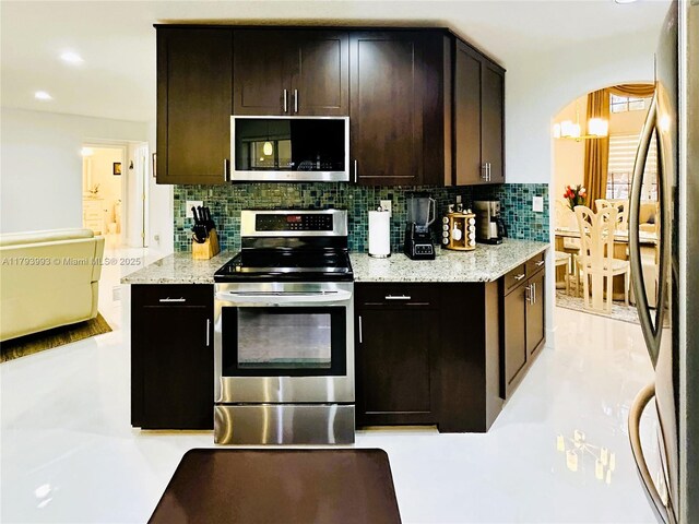 16541 Turquoise Trl, Weston, FL 33331 - kitchen featuring appliances with stainless steel finishes, decorative backsplash, arched walkways, light stone countertops, and recessed lighting