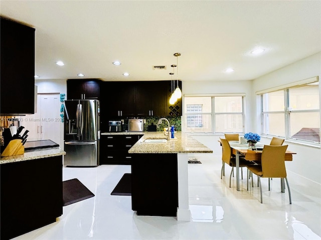 16541 Turquoise Trl, Weston, FL 33331 - kitchen with stainless steel fridge with ice dispenser, dark cabinets, tasteful backsplash, hanging light fixtures, and light stone counters