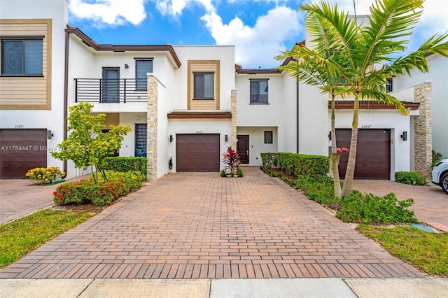 view of property with decorative driveway, stucco siding, and a balcony