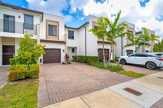 view of property featuring a garage, stucco siding, and decorative driveway