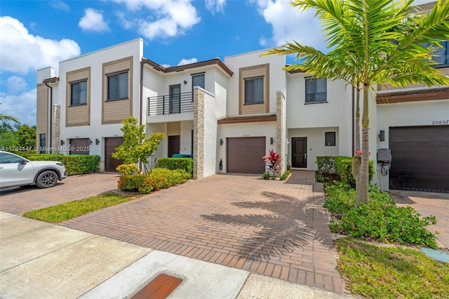 view of property featuring a garage, stucco siding, driveway, and a balcony