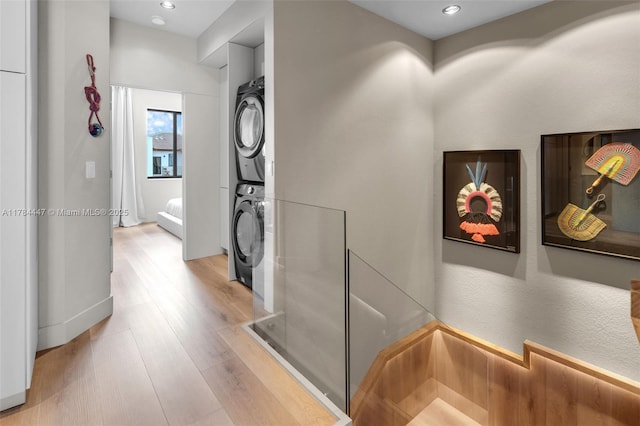 hallway with recessed lighting, light wood-style flooring, and stacked washer / dryer