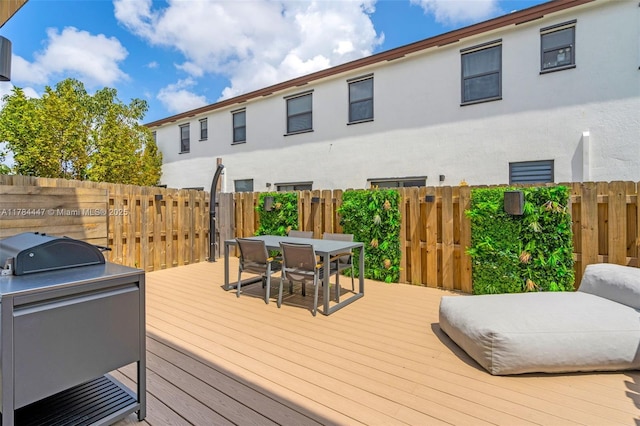 wooden terrace with fence, exterior kitchen, outdoor dining space, and grilling area