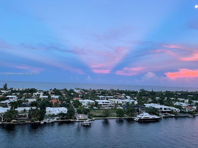 aerial view at dusk with a water view and a residential view