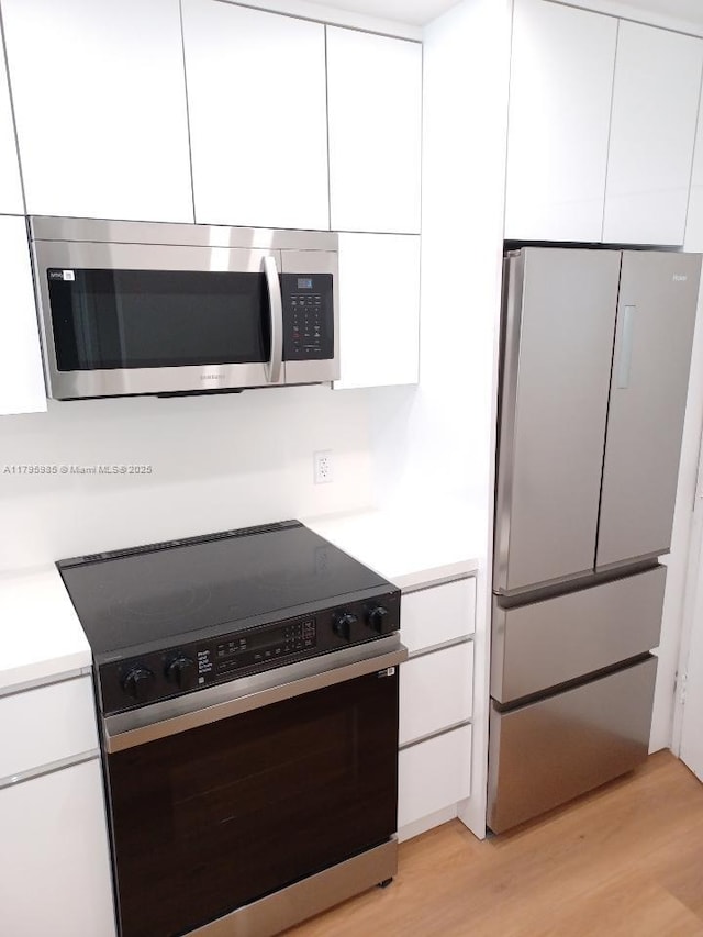 kitchen with modern cabinets, stainless steel appliances, and white cabinetry