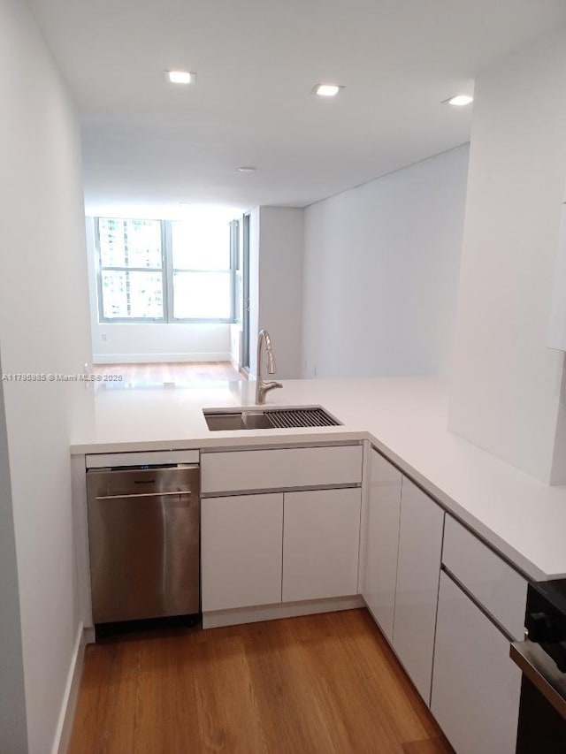 kitchen with a sink, white cabinets, stainless steel dishwasher, and light wood finished floors