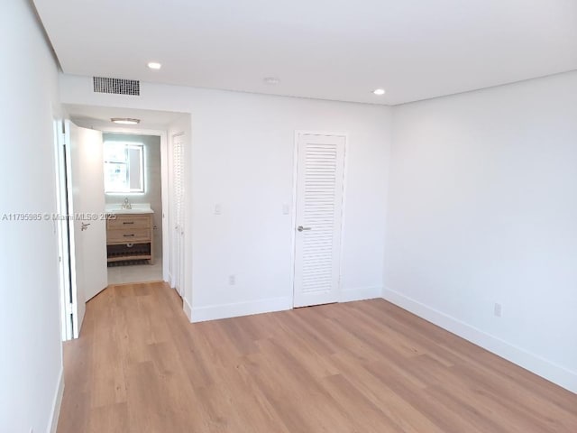 unfurnished bedroom featuring visible vents, light wood-style floors, baseboards, and a closet