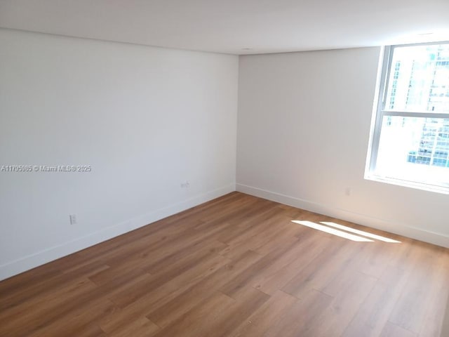 spare room featuring baseboards and light wood finished floors