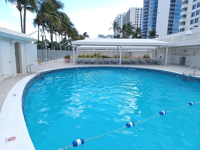 pool with a gazebo, fence, and a patio area