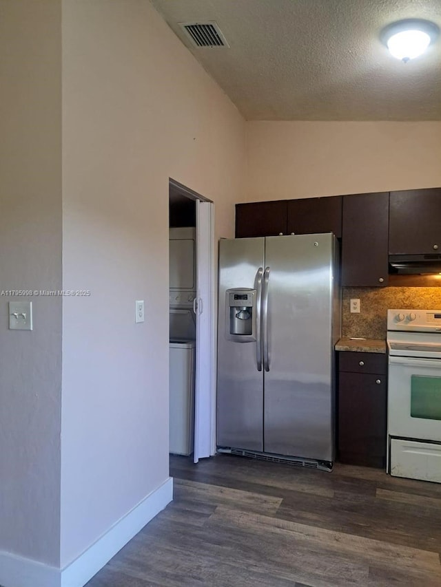 kitchen featuring stacked washer / dryer, vaulted ceiling, stainless steel refrigerator with ice dispenser, visible vents, and white electric range