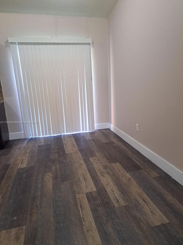 spare room with baseboards and wood finished floors