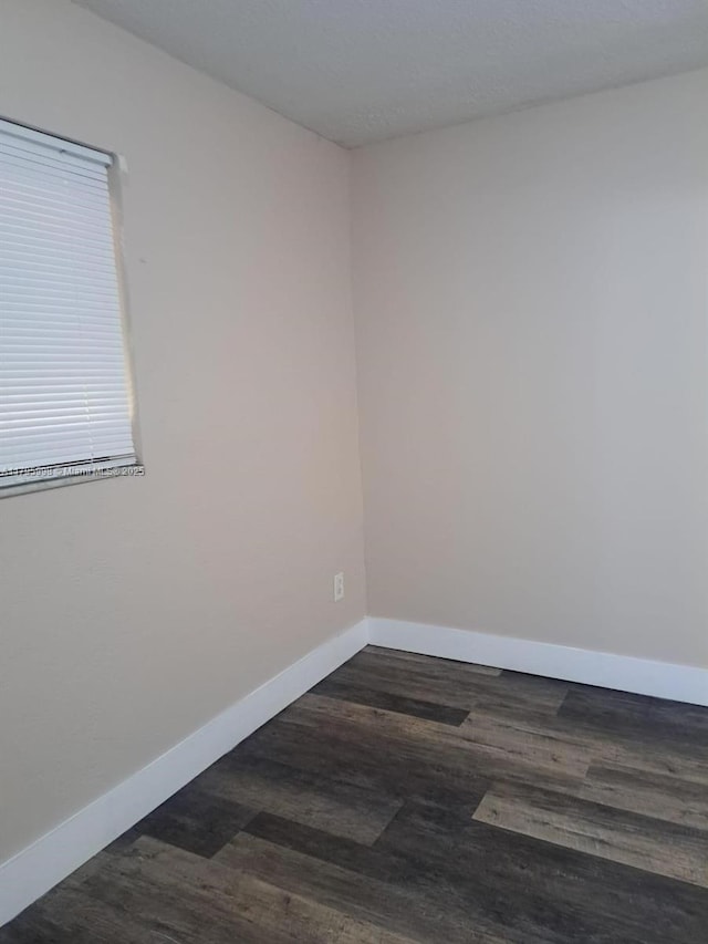 empty room featuring baseboards and dark wood-style floors